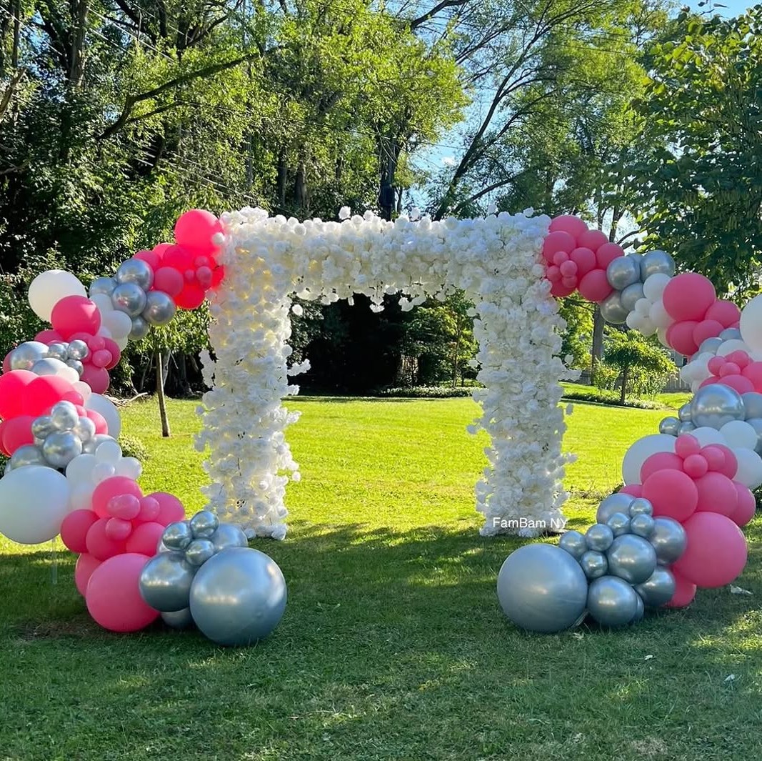 Pink and silver balloon arch with white floral pillars